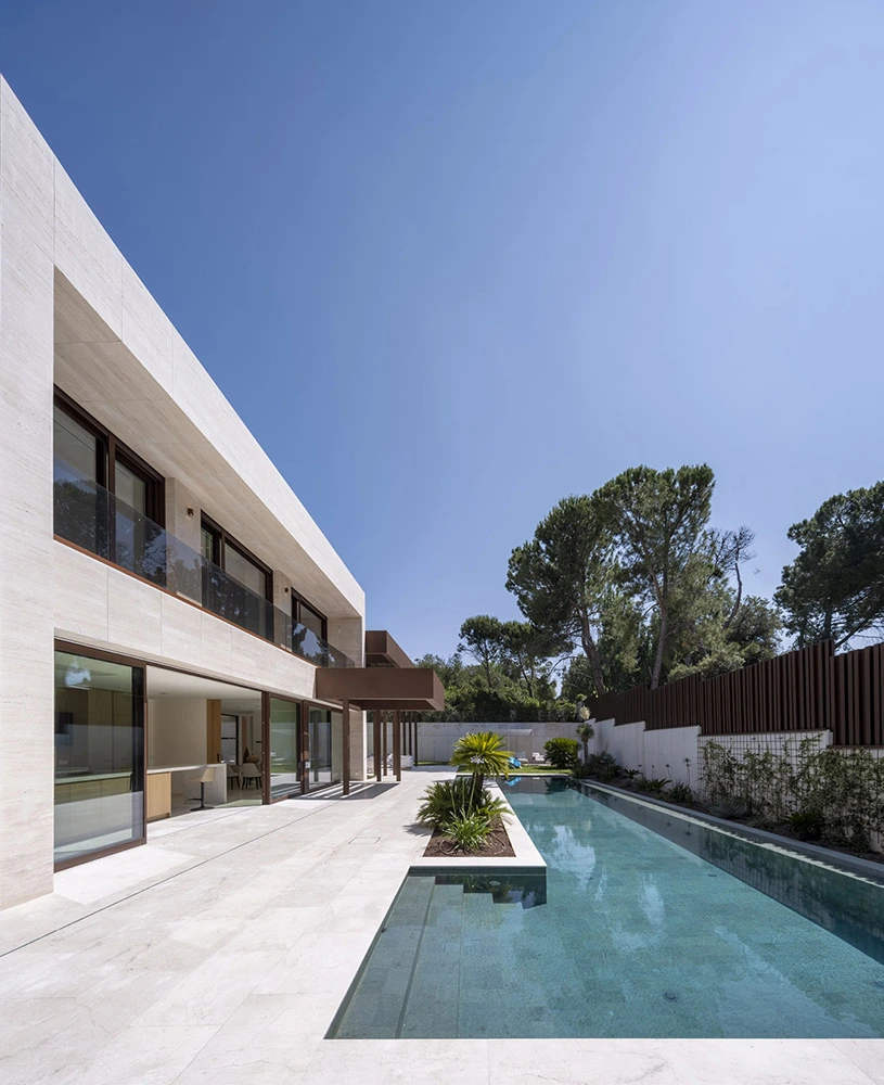 Vivienda contemporánea con piscina longitudinal y arquitectura minimalista Casa moderna con fachada en piedra clara y piscina alargada junto a la terraza exterior
