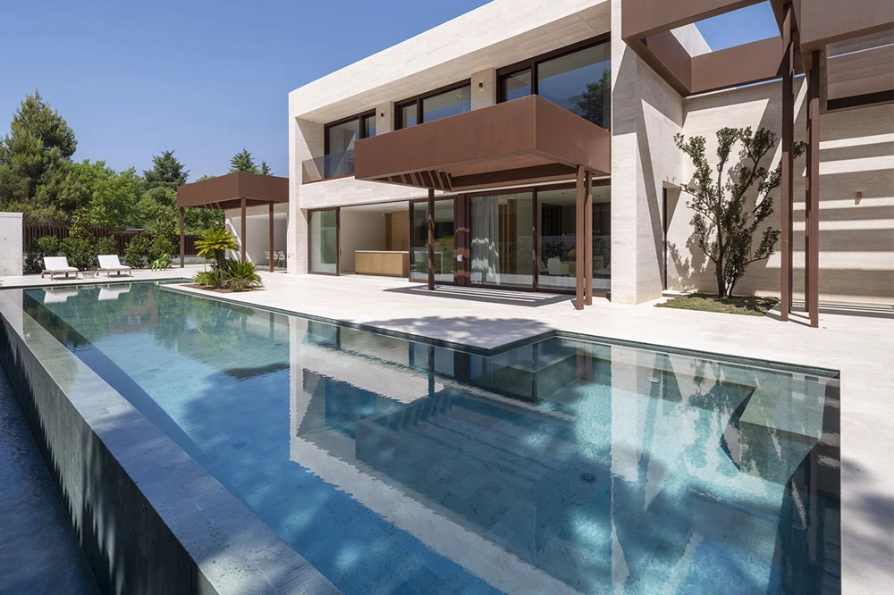 Piscina desbordante y terrazas voladas en vivienda de lujo Piscina infinita frente a vivienda moderna con terrazas flotantes y ventanales panorámicos